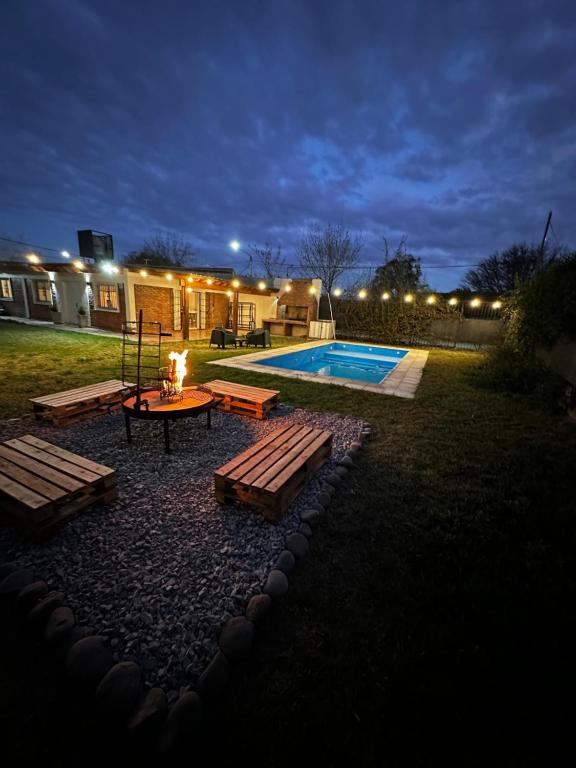 een achtertuin met een zwembad met een tafel en banken bij Casa entre Viñas y Montaña in Mendoza