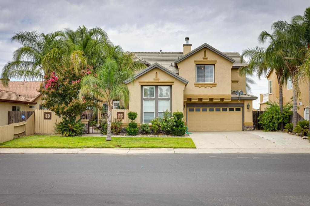 a house with a garage and palm trees at Family-Friendly Manteca Vacation Rental with Pool! in Manteca