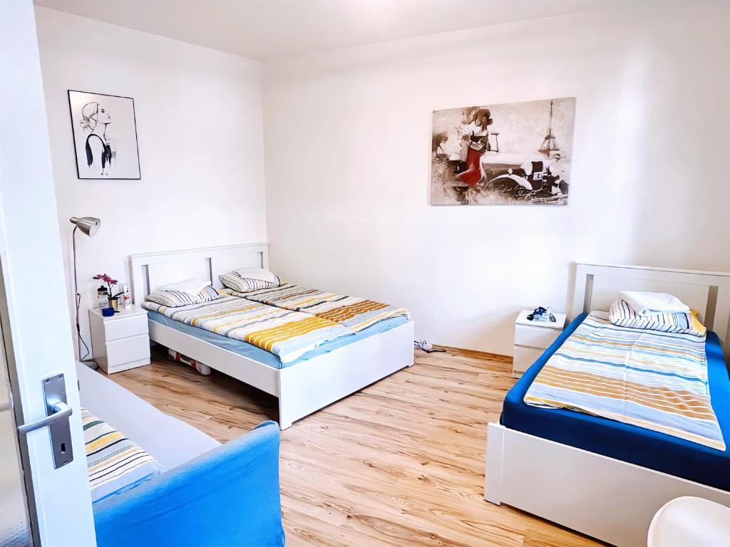 2 Betten in einem Zimmer mit weißen Wänden und Holzböden in der Unterkunft Vienna Prater Apartments in Wien