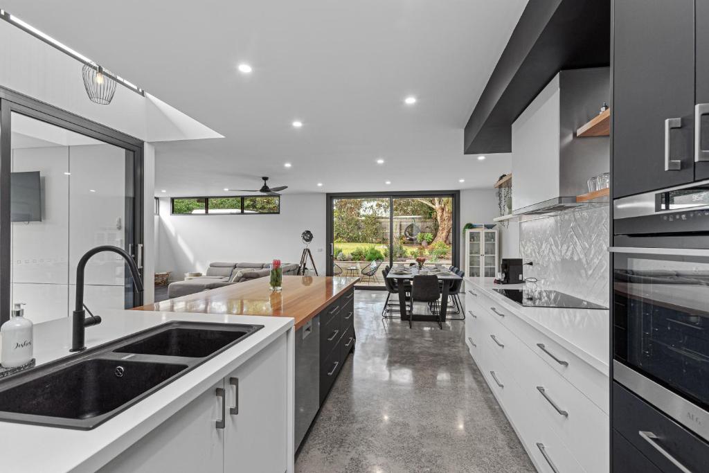 een keuken met zwart-witte apparatuur en een eetkamer bij Luxurious Haven House by the Beachside Ocean Grove in Ocean Grove