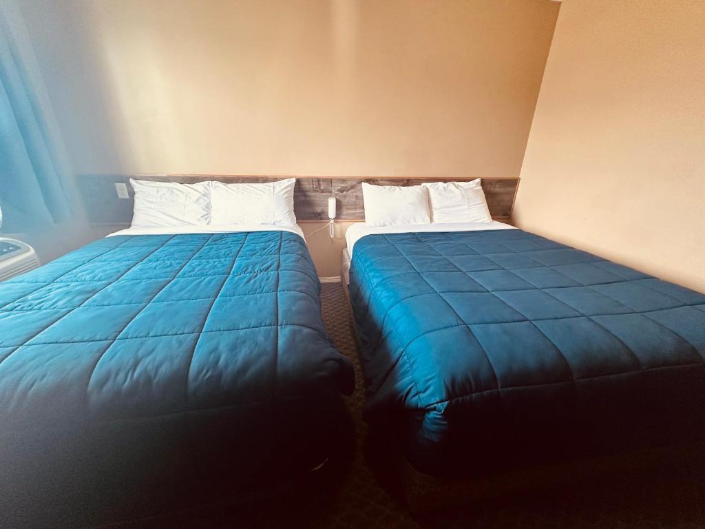 two beds sitting next to each other in a room at Voyageur Motel in Rocky Mountain House