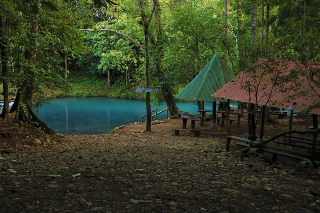 a picnic table and a tent next to a pond at Hotel SueñoReal RioCeleste in Rio Celeste