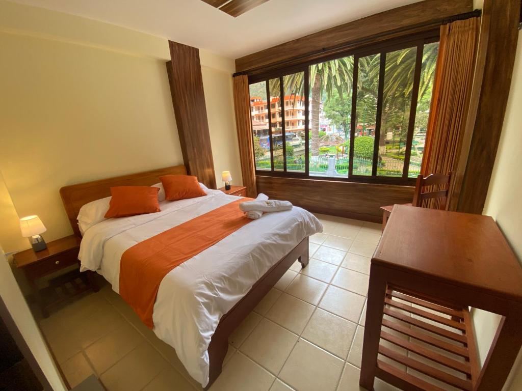 a bedroom with a bed and a desk and a window at Hostal Magdala in Baños