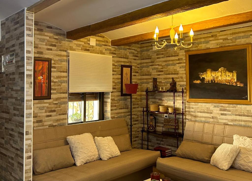 sala de estar con sofá y pared de ladrillo en Casa Rural La Simona, en Belmonte