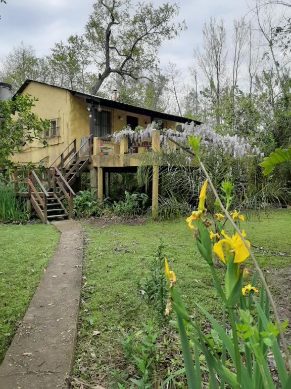 una casa amarilla con un porche en un patio en Delta Rose Farm en Tigre