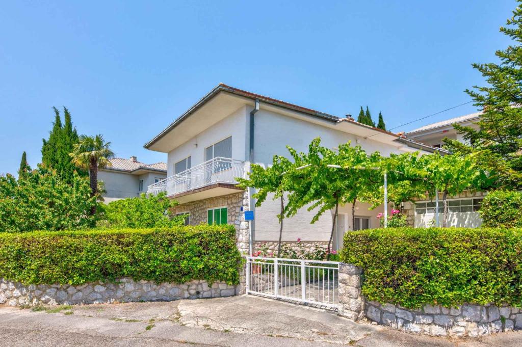 a house with a fence and bushes in front of it at Apartments in Crikvenica 41682 in Crikvenica