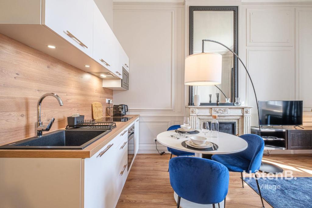 une cuisine avec un évier et une table avec des chaises bleues dans l'établissement The Little Cérez Luminous Studio in the Heart of Limoges, à Limoges