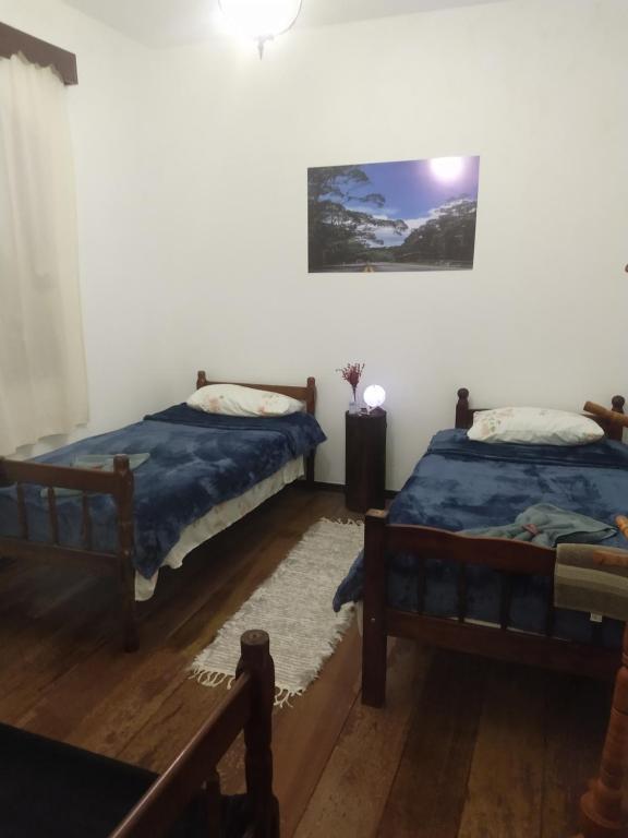 a bedroom with two beds and a picture on the wall at Pousada Canto do Sertão in São Miguel Arcanjo