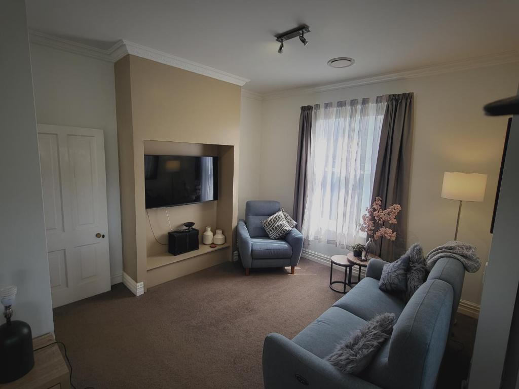 uma sala de estar com um sofá azul e duas cadeiras em Central Victoria Oasis em Hamilton