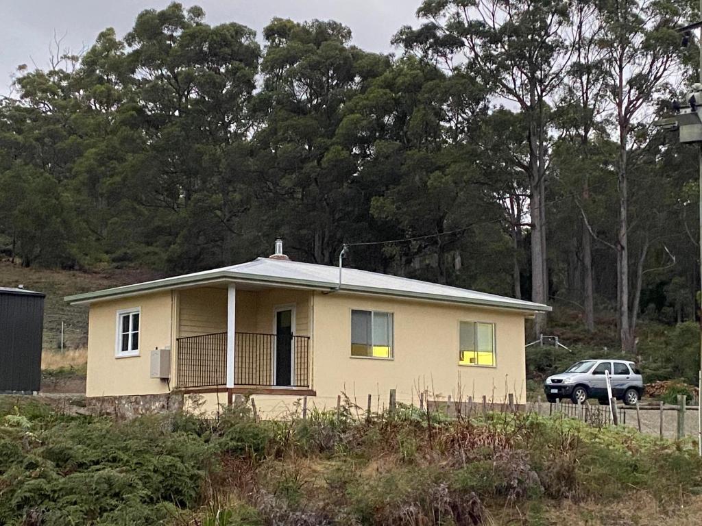 una casa gialla con una macchina parcheggiata di fronte di Aruma Cottage Bruny Island ad Alonnah