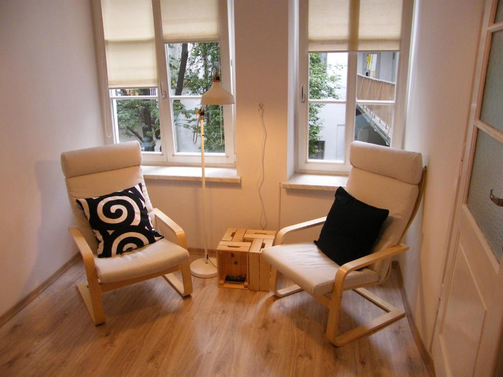 two chairs and a table in a room with windows at Apartament Jagielloński in Krakow