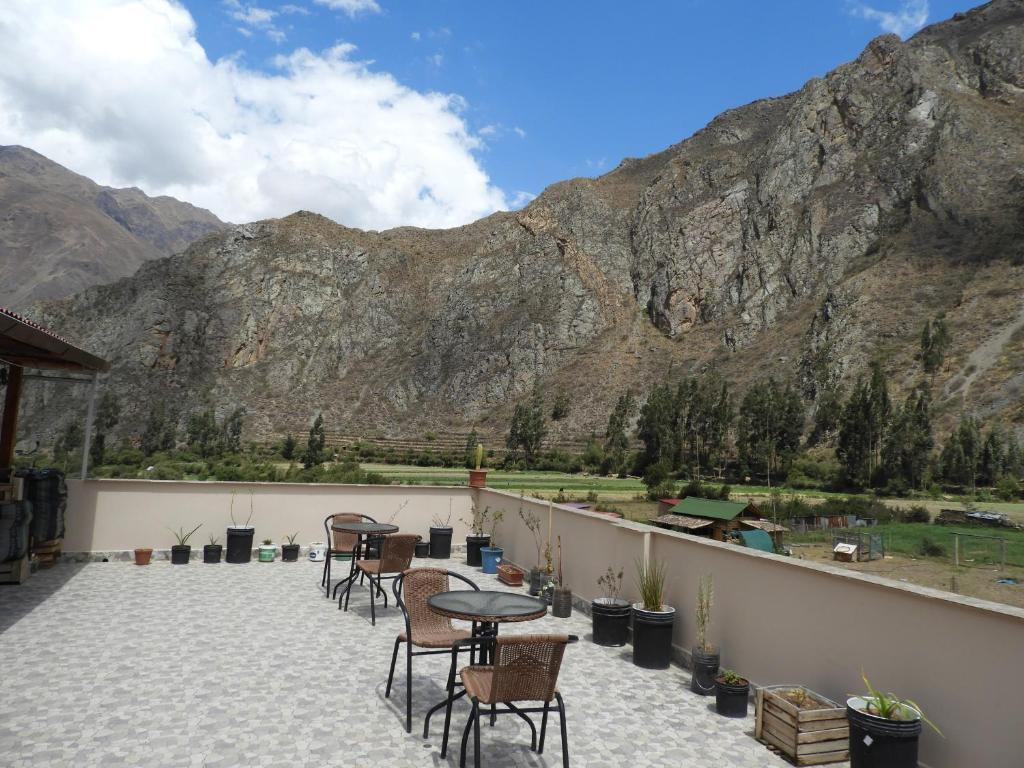a patio with tables and chairs with mountains in the background at Ayllu B&B Ollantaytambo in Ollantaytambo