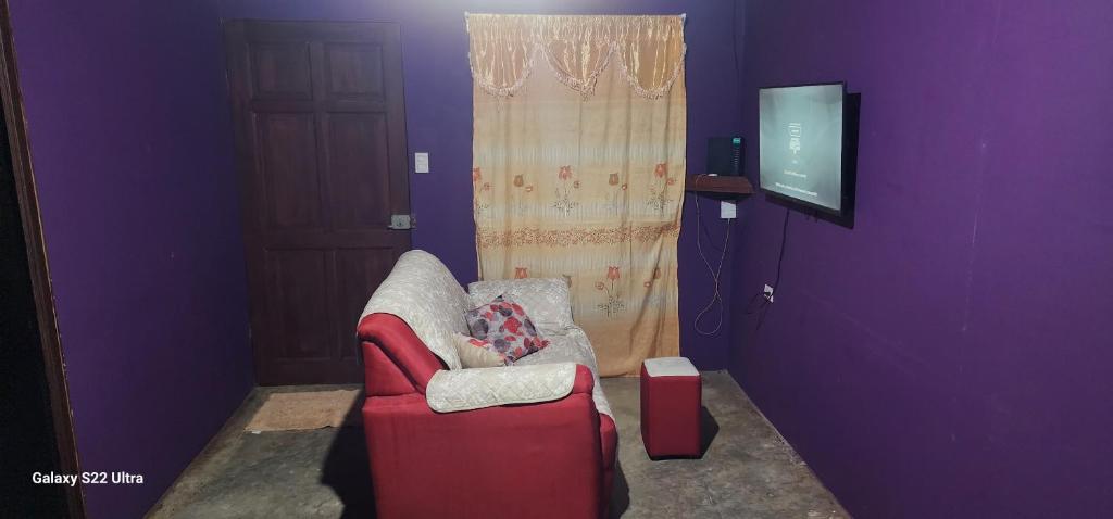 Habitación púrpura con silla roja y TV en Refugio Valverde Alonso, en Puerto Jiménez