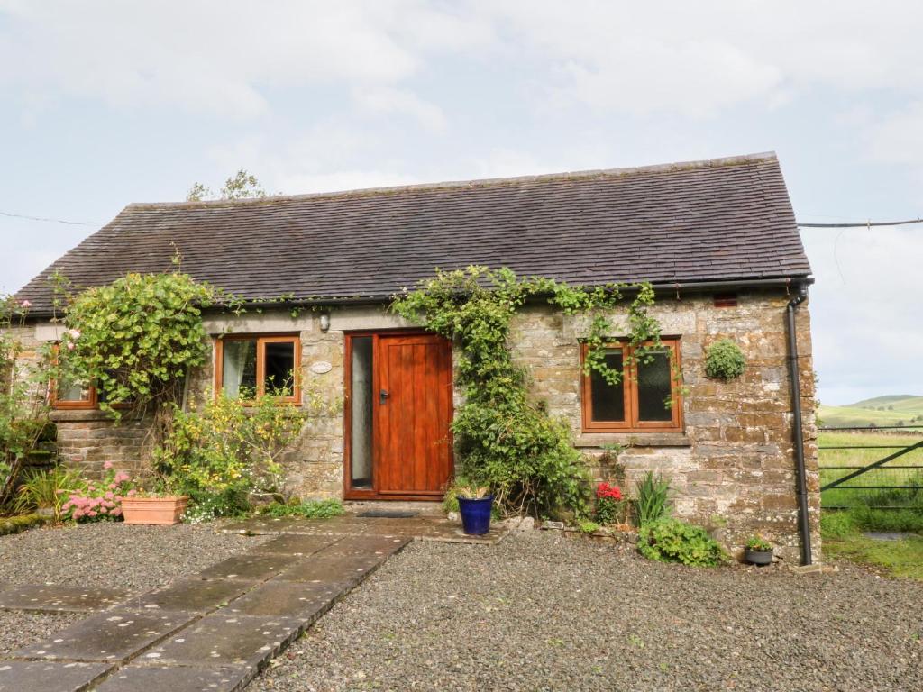a small stone cottage with a wooden door at Manifold Cottage in Grindon
