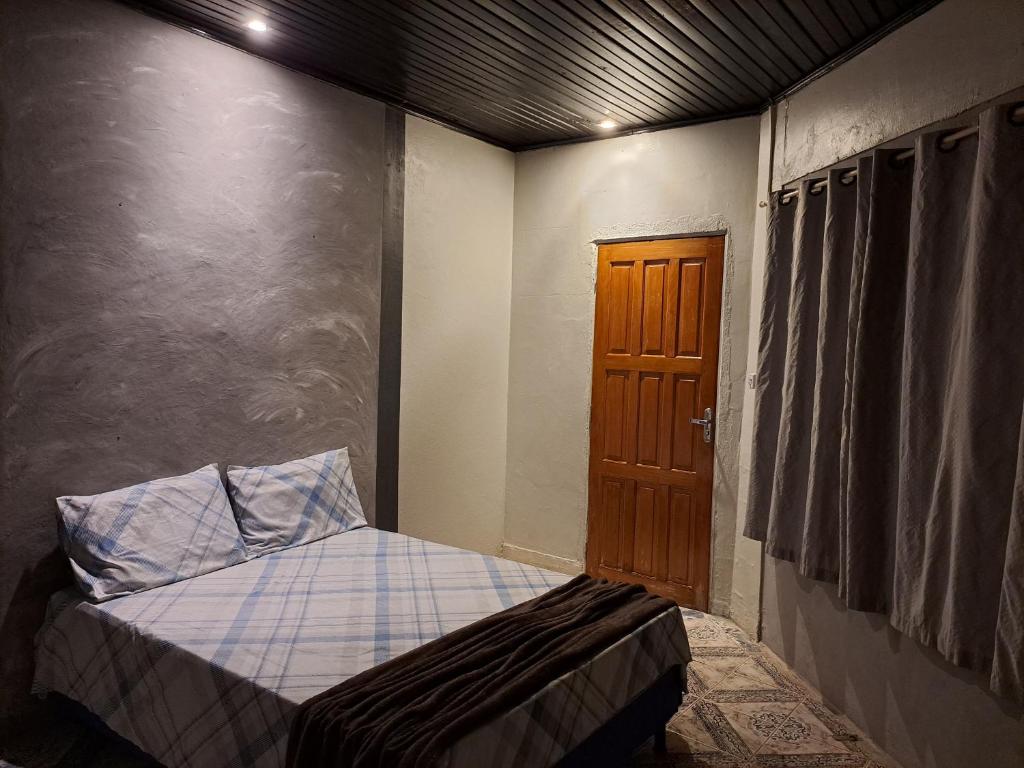 a small bedroom with a bed and a wooden door at AP 3 - Suíte Confortável e Aconchegante - Pousada Paraíso in Macapá