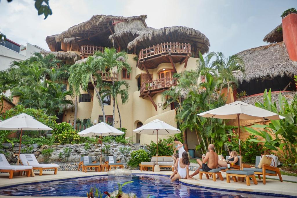 un grupo de personas sentadas en una piscina frente a un edificio en La Villa Luz (sólo adultos) en Zihuatanejo