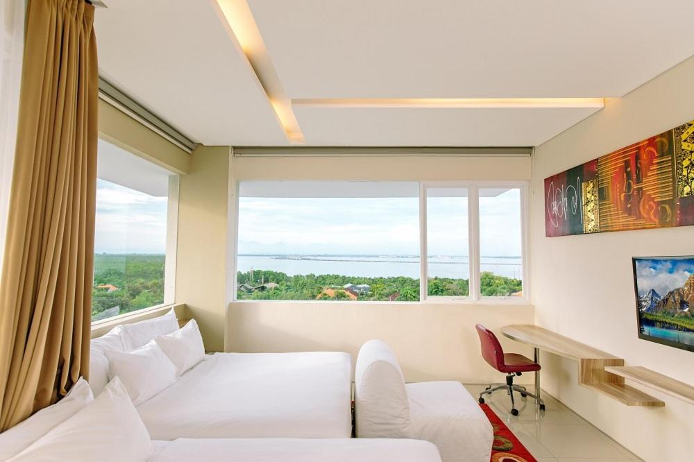 sala de estar con sofá blanco y ventana grande en Mahogany Hotel, en Nusa Dua