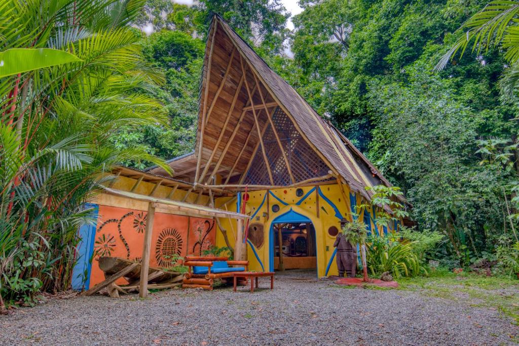 a house with a thatched roof in a forest at Tree House Beachfront Lodge in Puerto Viejo
