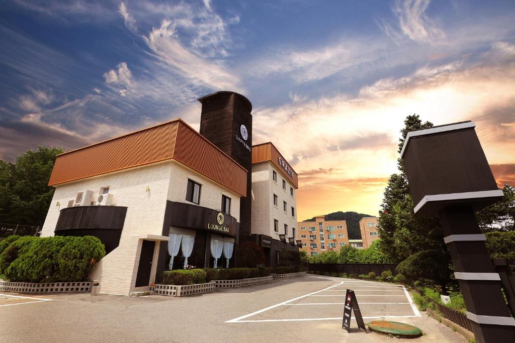 a building with a clock tower in a parking lot at Gapyeong Grache Hotel in Gapyeong