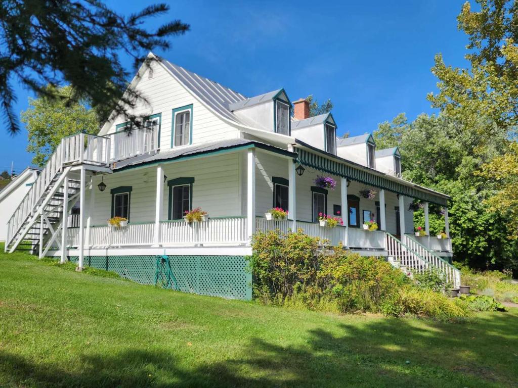 a white house with flowers on the front of it at Auberge des Nuages in La Malbaie