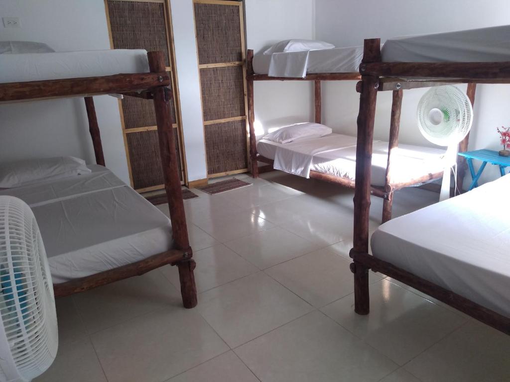 a room with four bunk beds and a white floor at Hostal El Nido del Azulejo in Barú