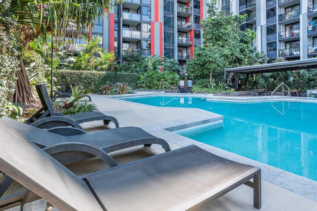 a swimming pool with chairs next to a building at Vibrant Inner City Living 1 bedroom Apartment in Brisbane