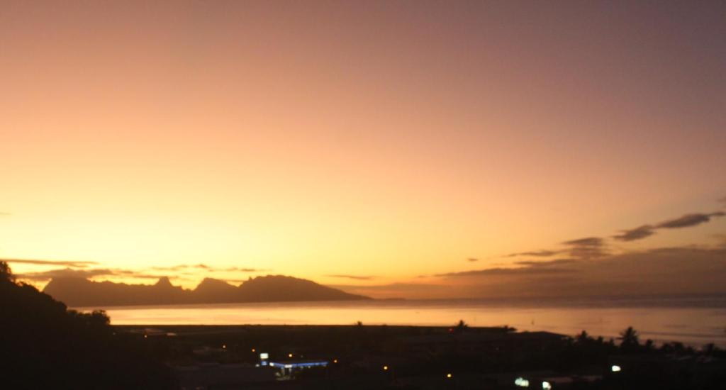 a sunset over the water with a city at Tahiti Diva Sunset studio in Papeete