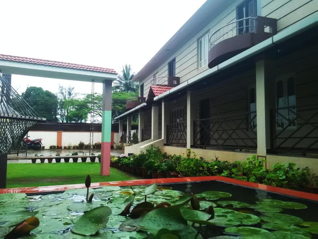 dom ze stawem przed nim w obiekcie Lotus The Cottages w mieście Madikeri