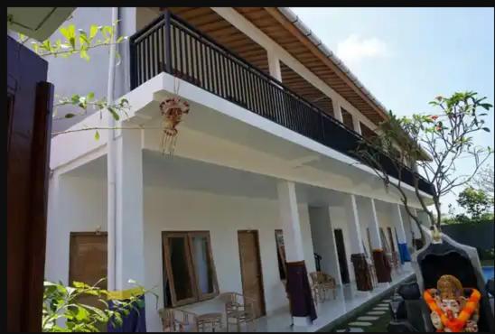 a white house with a balcony on top of it at Double D Guest House Canggu in Canggu