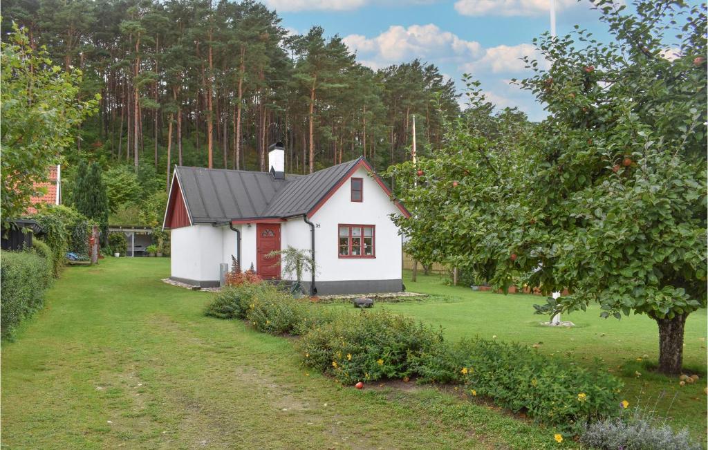 een klein wit huis met een zwart dak in een tuin bij Amazing Home In Kivik With Wifi in Kivik