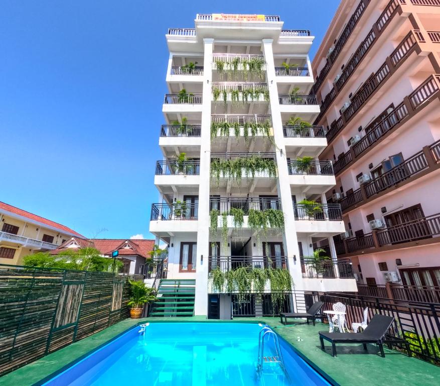 an apartment with a swimming pool in front of a building at Vang Vieng Consiana Hotel in Vang Vieng