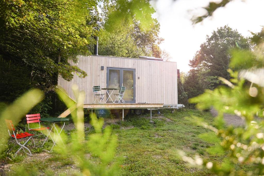 une petite maison avec une table et des chaises dans une cour dans l'établissement Green Tiny Village Harz - Tiny House Pioneer 7, à Osterode