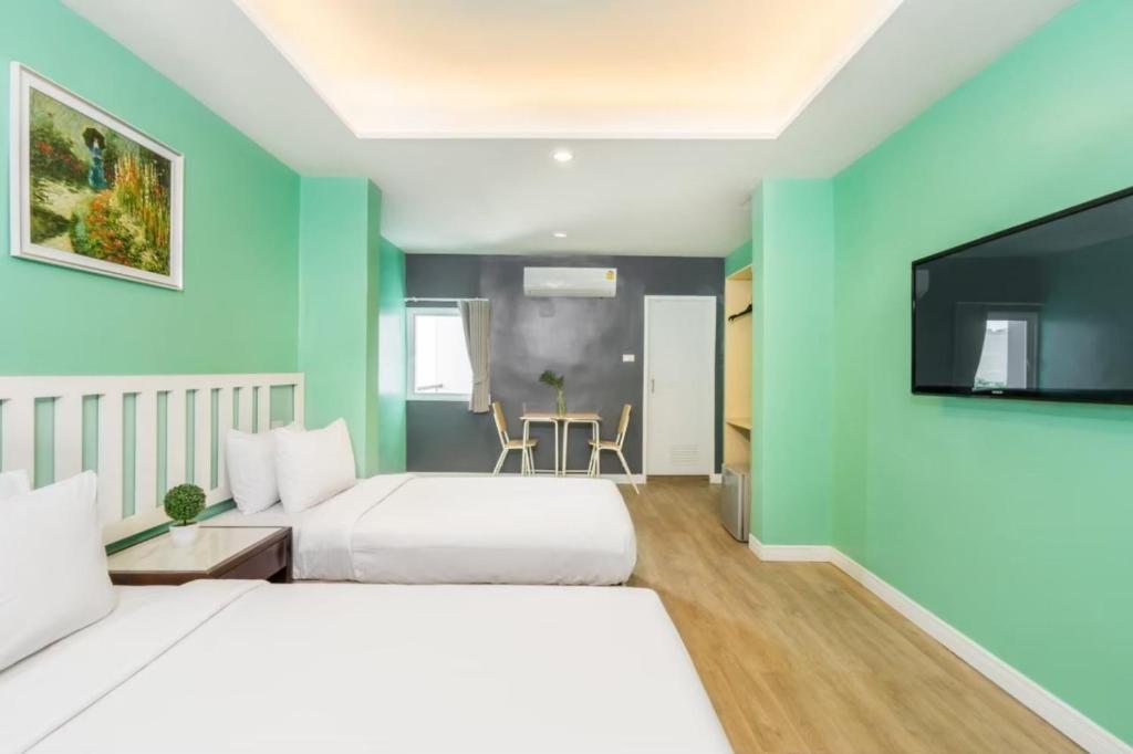 a hotel room with two beds and a flat screen tv at Metro Link Ratchada Hotel in Bangkok