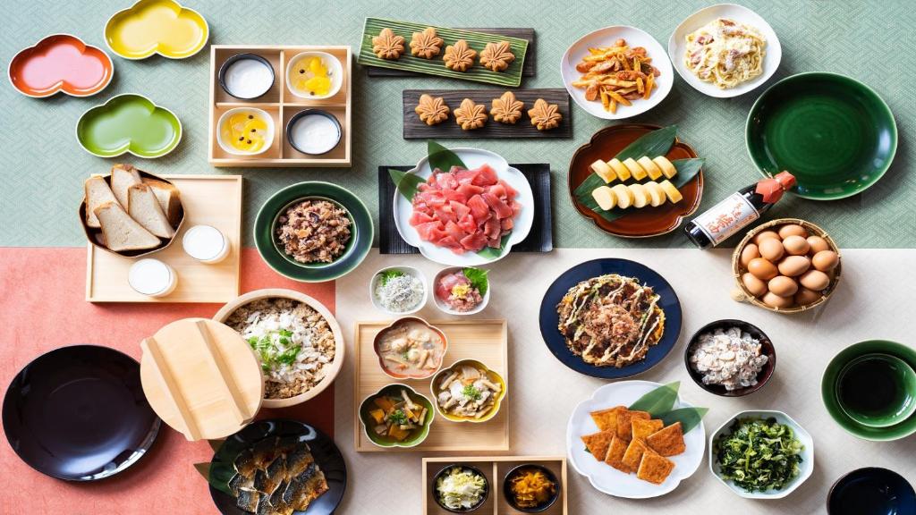a table with plates of food and bowls of food at Vessel Inn Fukuyama Eki Kitaguchi in Fukuyama