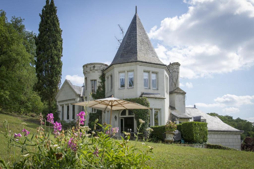 an old house with an umbrella in the yard at Chambres d'Hôtes Manoir de Montecler in Chènehutte-les-Tuffeaux