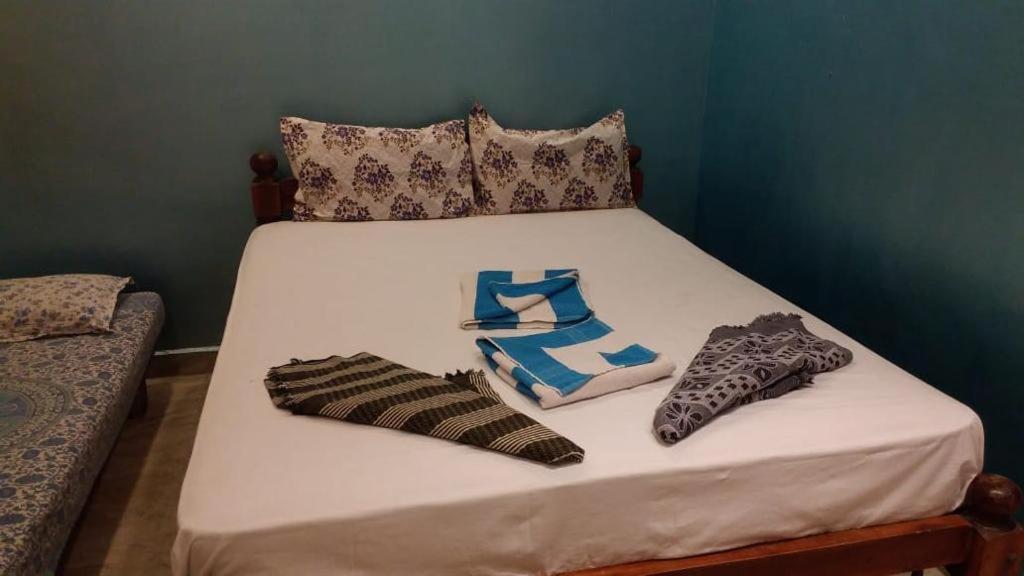 a white bed with two pillows and socks on it at La Gabriell beach inn in Calangute