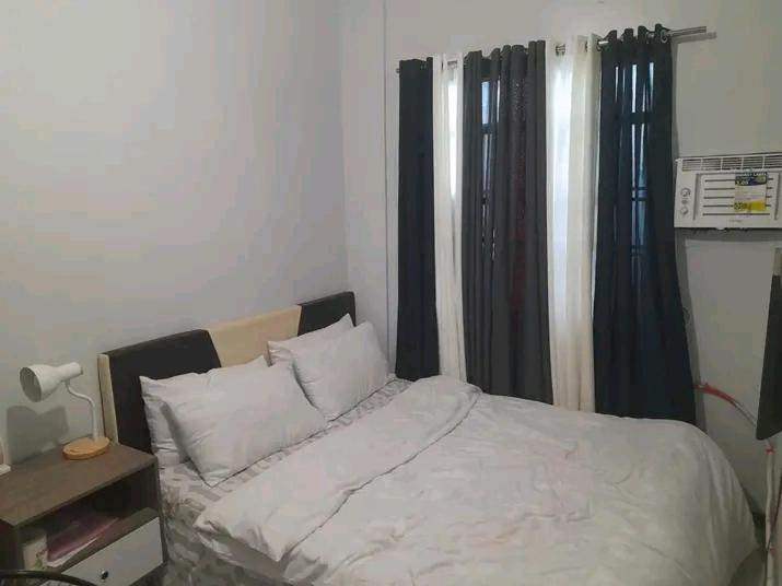 - une chambre avec un lit blanc et des rideaux noirs dans l'établissement Unique apartment, à Nsukka
