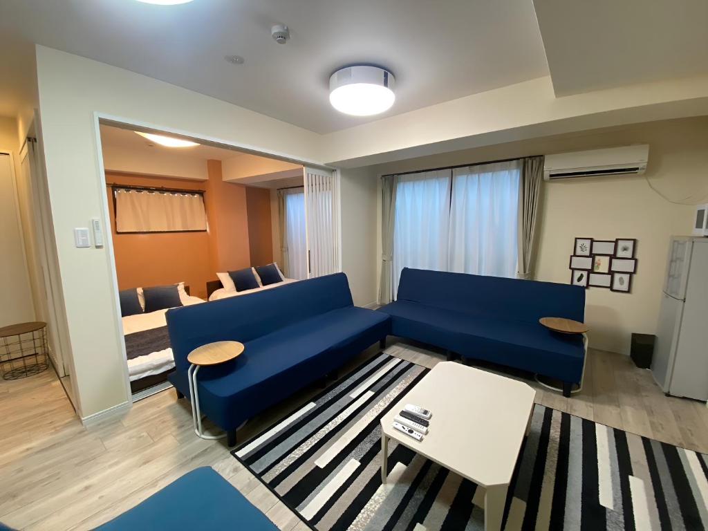 a living room with a blue couch and a table at Sincere Residence in Osaka
