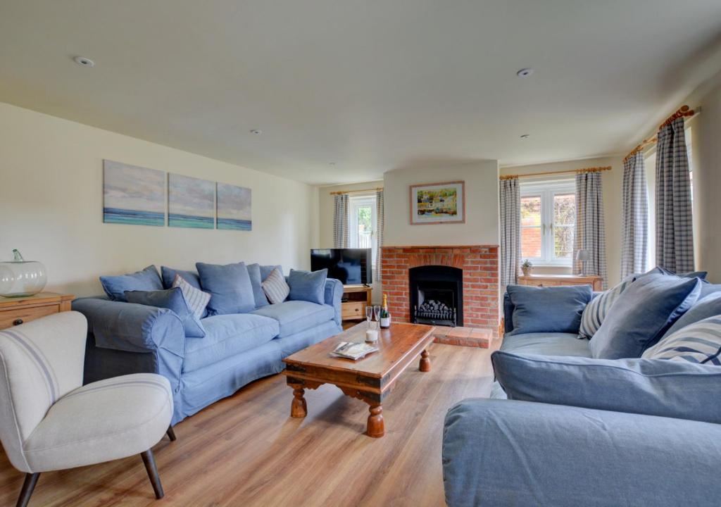 a living room with blue couches and a fireplace at Finder's Cottage in Docking