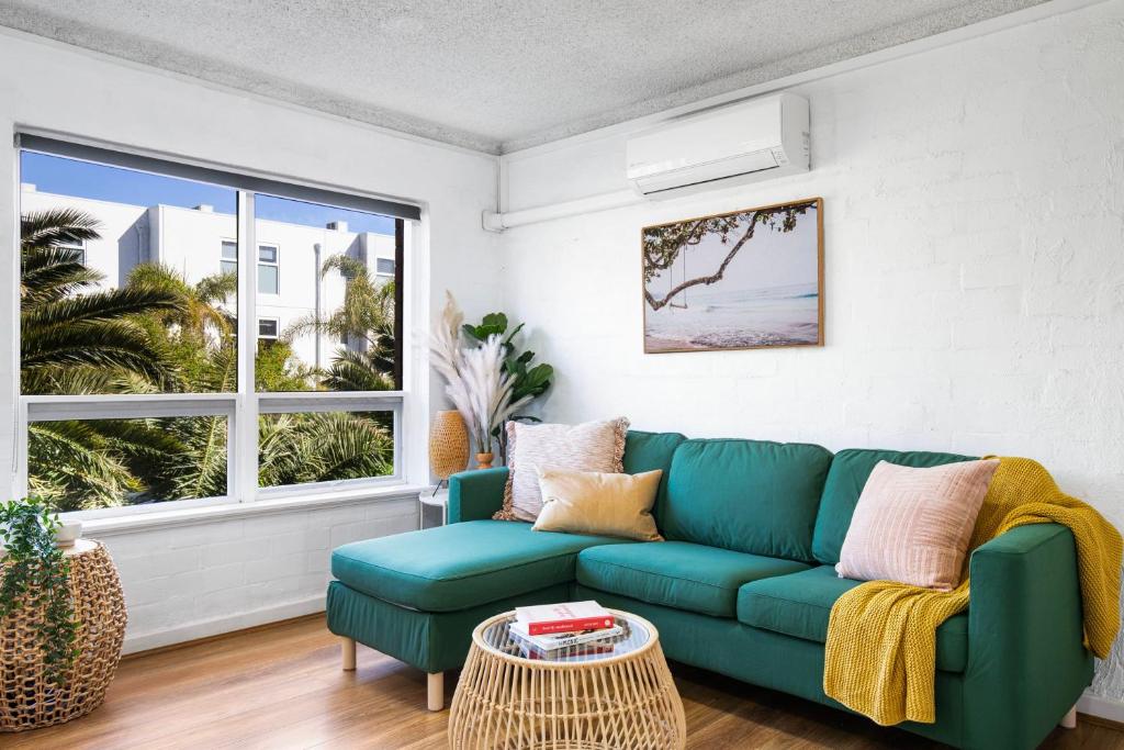 a living room with a green couch and a window at Ray's Place by the Riverside in Glenelg