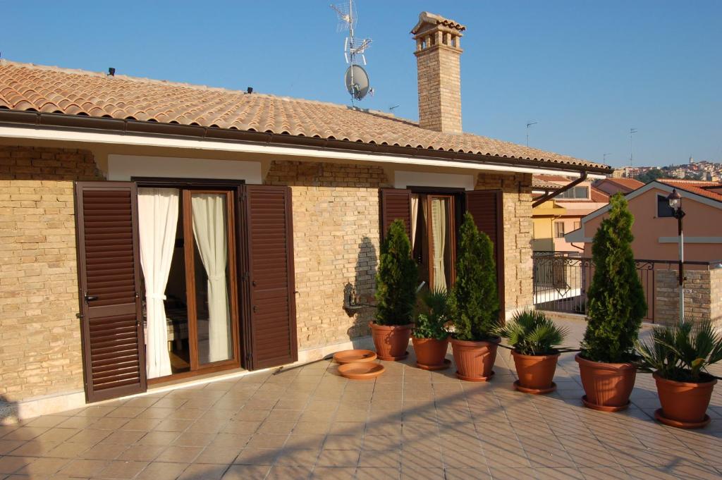 ein Haus mit Holztüren und Topfpflanzen auf einer Terrasse in der Unterkunft Piccolo Marte in Montenero di Bisaccia
