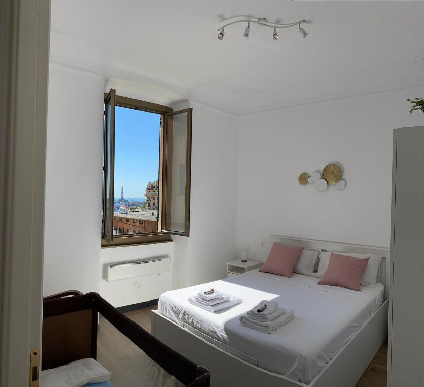 Un dormitorio con una cama con almohadas rosas y una ventana en La finestrella sul porto, en Génova
