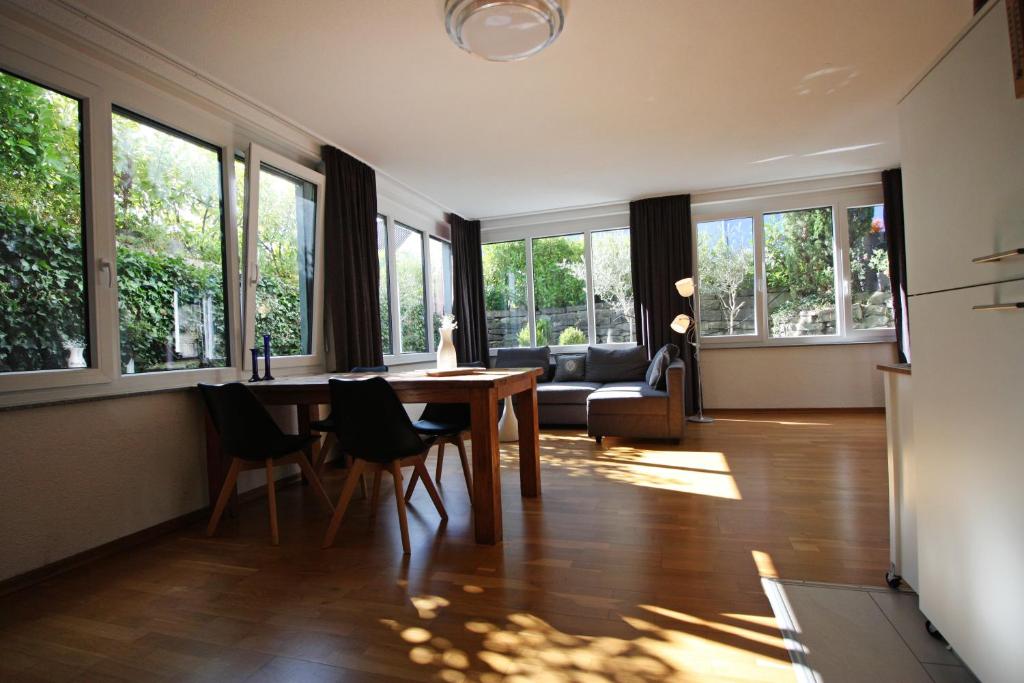 - un salon avec une table, des chaises et des fenêtres dans l'établissement Konstanzer Ferienwohnungen, à Constance