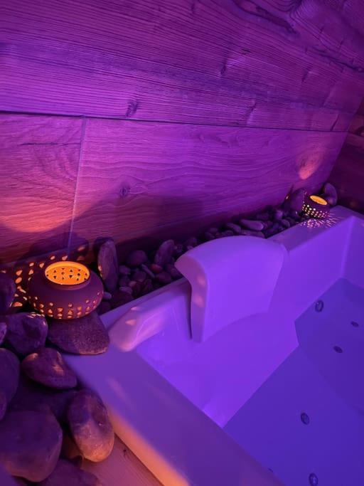 a purple room with a tub and some rocks at Zen Room in LʼIsle-sur-le-Doubs