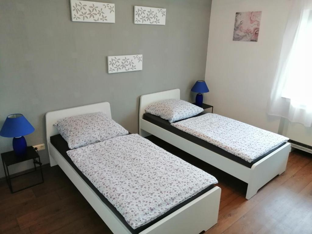 2 camas individuales en una habitación con 2 lámparas en Haus Mohr - Ferienwohnung im Taunus, en Weilmünster