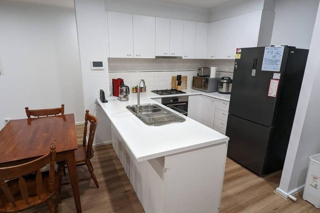 een keuken met een wit aanrecht en een zwarte koelkast bij 3 bedroom condo opposite casino. in Melbourne
