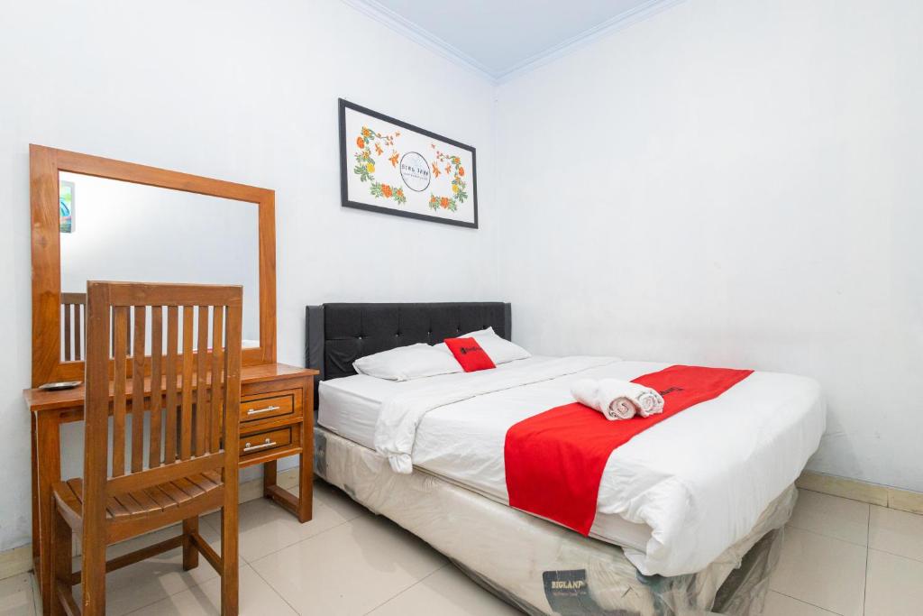 a bedroom with a bed and a desk and a mirror at RedDoorz near Wisata Museum Angkut 3 in Batu
