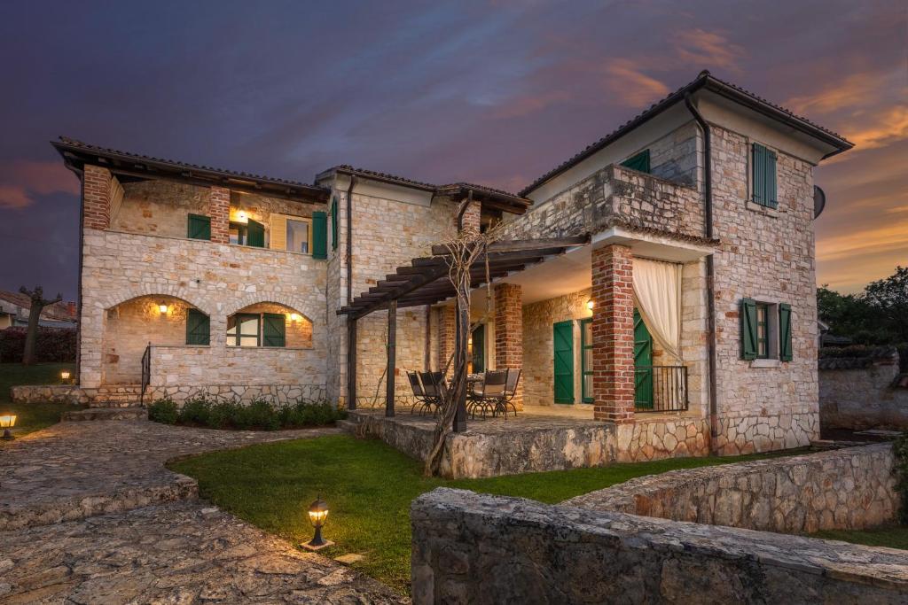 a large stone house with a fence in front of it at Villas Orbani by Istarski Dvori in Sveti Lovreč Pazenatički