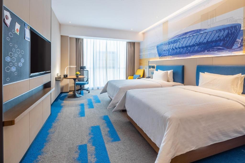 QingshanにあるHampton by Hilton Wuhan High-Speed Railway Stationのベッド2台、薄型テレビが備わるホテルルームです。