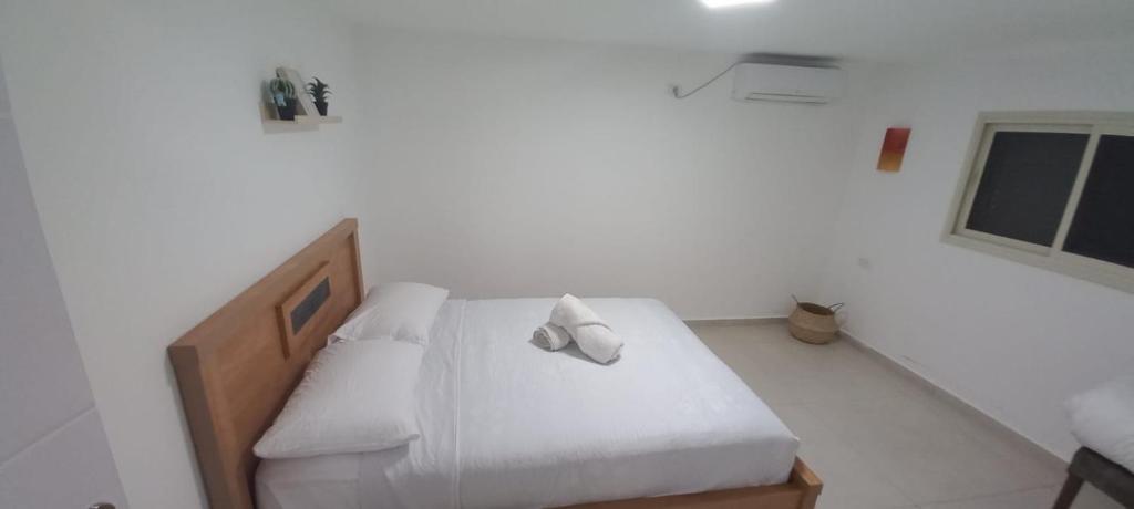 um quarto com uma cama com lençóis brancos e uma janela em לב במדבר - הצימר של רחלי em Arad